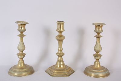 three gold candlesticks sitting next to each other on a white surface