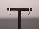 une paire de boucles d'oreilles créoles en diamant posées sur un présentoir noir