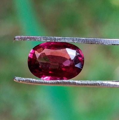 un gros plan d'une pierre précieuse rouge tenue par une pince