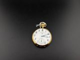 une petite montre de poche en or posée sur une surface noire