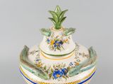 a white vase with a green leaf on top of it