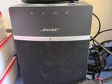 a black speaker sitting on top of a desk next to a charger
