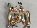 two birds sitting on a tree branch with green crystals in their beaks
