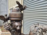 a bronze statue of a boy and a bird on a fire hydrant