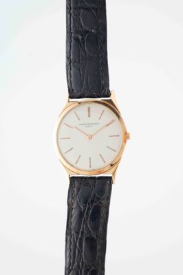 a close up of a wrist watch with a white face and black leather strap