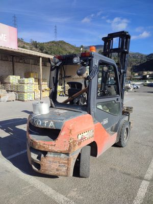 a forklift truck parked in a parking lot in front of a store