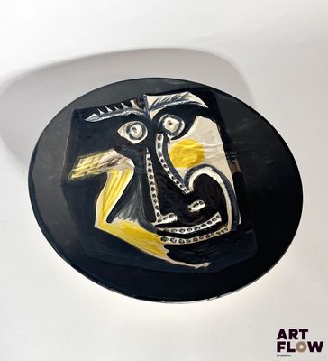 a black plate with a yellow and white painting on it