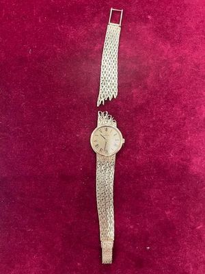une montre en argent posée sur une surface en velours rouge