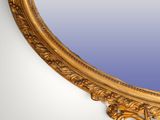 an oval mirror with a gold frame and a blue background