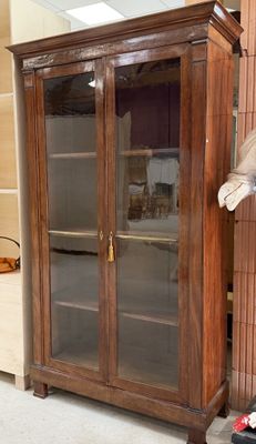 un grand meuble en bois avec des portes en verre dans une pièce