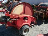 un tracteur rouge avec un tuyau fixé à l'arrière