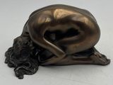 sculpture en bronze représentant une femme allongée sur le dos sur une surface blanche