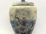a blue and white vase with a lid on a white surface