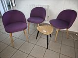 three purple chairs and a table in a room with a radiator