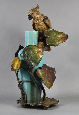 statue représentant un perroquet perché sur une branche d'une plante dans un vase