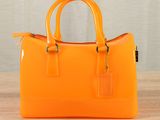 an orange handbag sitting on top of a wooden table