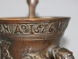 a close up of a bronze vase with a dog on it