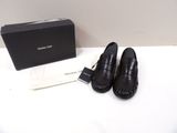 des mocassins en cuir noir, avec une boîte posée sur une table à côté