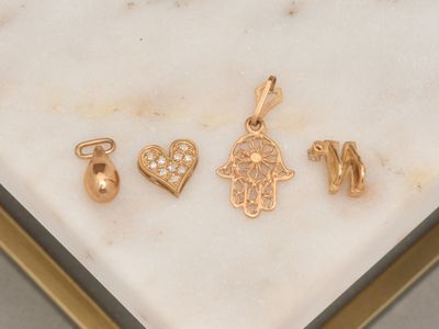 three gold - plated charms on a marble surface in a gold frame