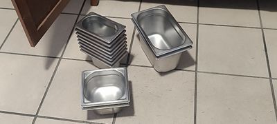 quatre casseroles remplies de nourriture sont posées sur le carrelage d'une cuisine