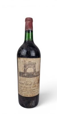 une vieille bouteille de vin posée sur une surface blanche