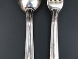 two silver spoons and a fork on a black surface