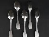 five silver spoons and a fork on a black surface