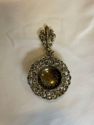 un gros plan d'un collier posé sur un tissu blanc, sur une table