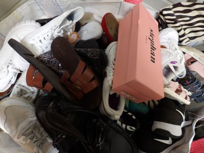 un tas de chaussures et une boîte rose sur un lit