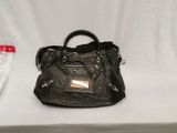 black leather handbag sitting on a white table next to a pair of jeans
