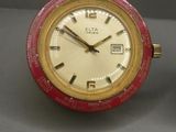 une horloge rouge et dorée posée à côté d'une horloge blanche
