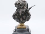 un buste antique en bronze représentant une femme tenant un couteau, posé sur un socle