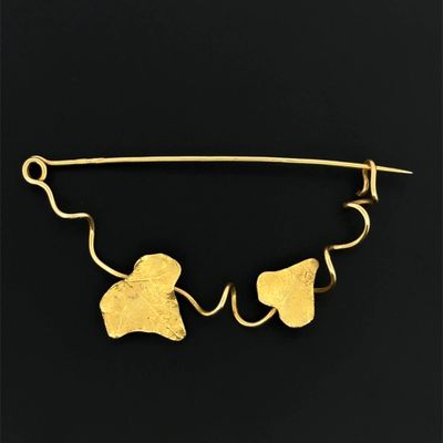 un gros plan sur une broche en or ornée de feuilles