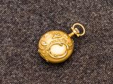 une image représentant une montre de poche en or posée sur un tissu