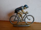 une figurine représentant un homme à vélo posée sur une table en bois