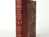 un vieux livre à la couverture rouge posé sur une table blanche