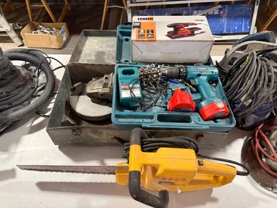 une boîte à outils posée sur une table à côté de deux tronçonneuses