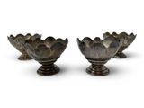 four metal bowls sitting on top of each other on a white surface