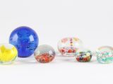 Plusieurs billes de verre sont alignées sur une surface blanche