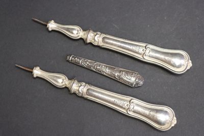 trois cuillères en argent et un couteau posés sur un plan de travail noir