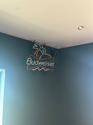 une enseigne lumineuse portant l'inscription « Budweiser » sur le mur d'une pièce