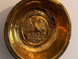 a gold plate with a bird on it hanging on a wall
