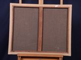 a wooden easel with a canvas on it against a blue background