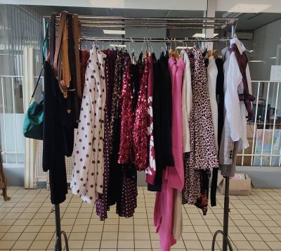 beaucoup de vêtements suspendus à une étagère dans une pièce