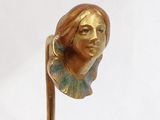 sculpture of a woman ' s head on a stick on a white surface
