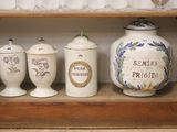 trois vases posés sur une étagère, avec des verres à vin en arrière-plan