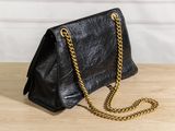 a black purse with gold chains on a wooden table