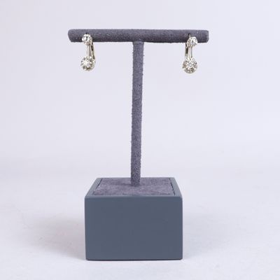 une paire de boucles d'oreilles en diamant posée sur un présentoir, sur fond blanc