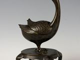 pair of bronze sculptures of a bird on a small stool
