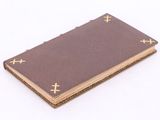 an old book with gold crosses on it sitting on a white surface